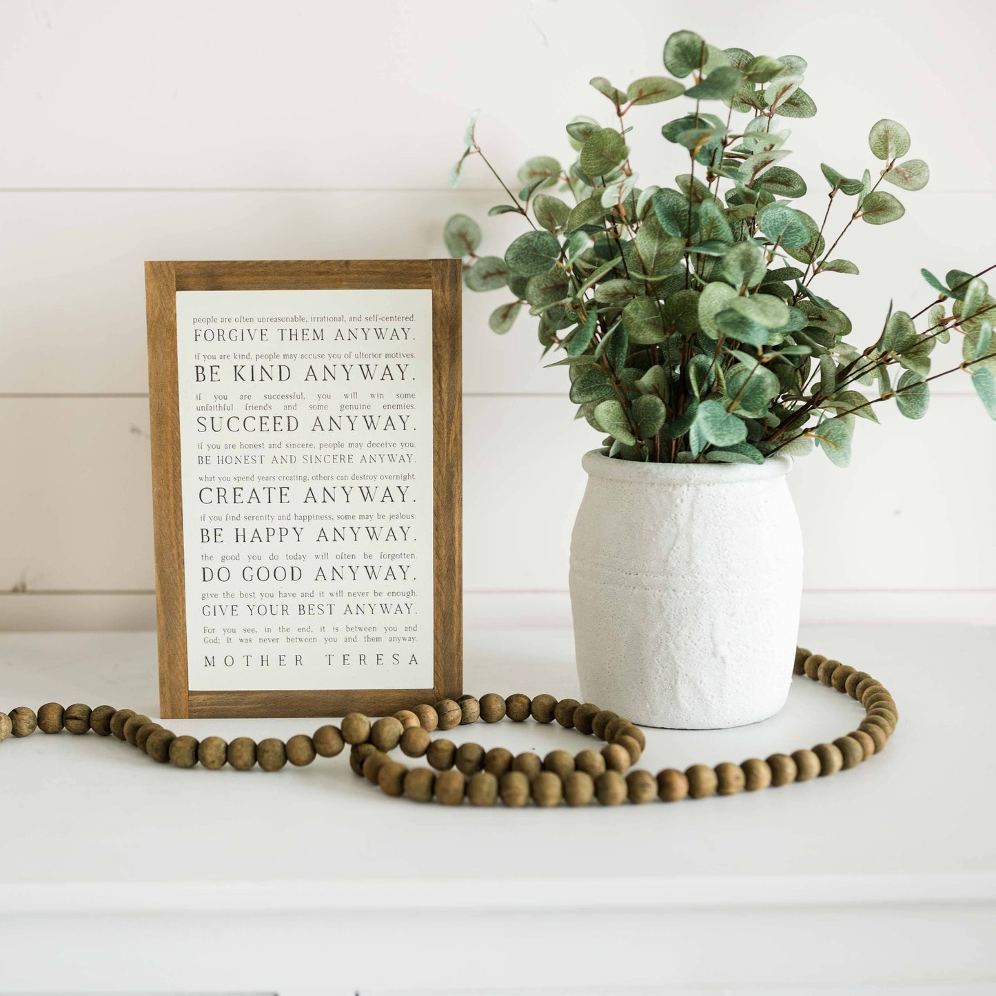 Love them Anyway | Mother Teresa | Wall Art: Soft White-Black Text / Light Brown Frame / 16 inches x 24 inches